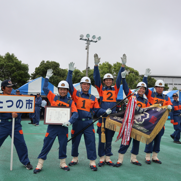 たつの市消防団龍野第10分団のみなさんが、大会の優勝旗と賞状を手に持って笑顔を見せている写真