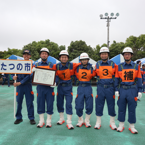 新宮第12分団のみなさんが、額入りの賞状を持って横並びになり、カメラに向かって笑顔を見せている写真
