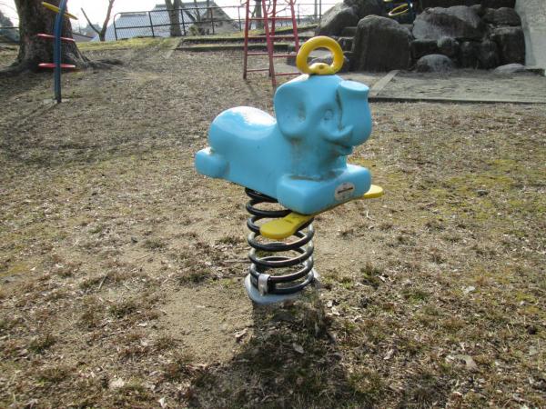 芝生の公園の中にある、青いゾウの形をしたスプリング遊具の写真