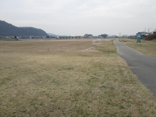 右側に奥に続く小道が写る芝の生えた祇園公園の広場の写真