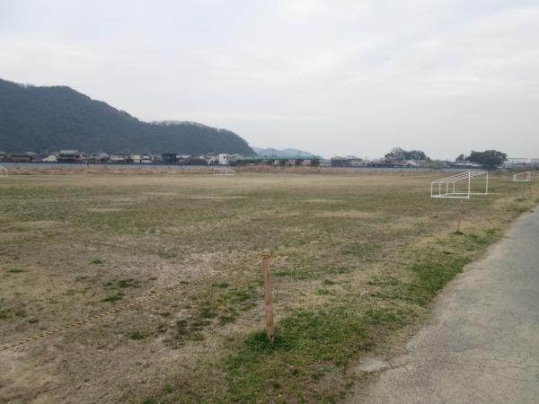 青々とした山を背景に芝生の広場が写され、画面右下に小道が見切れている写真