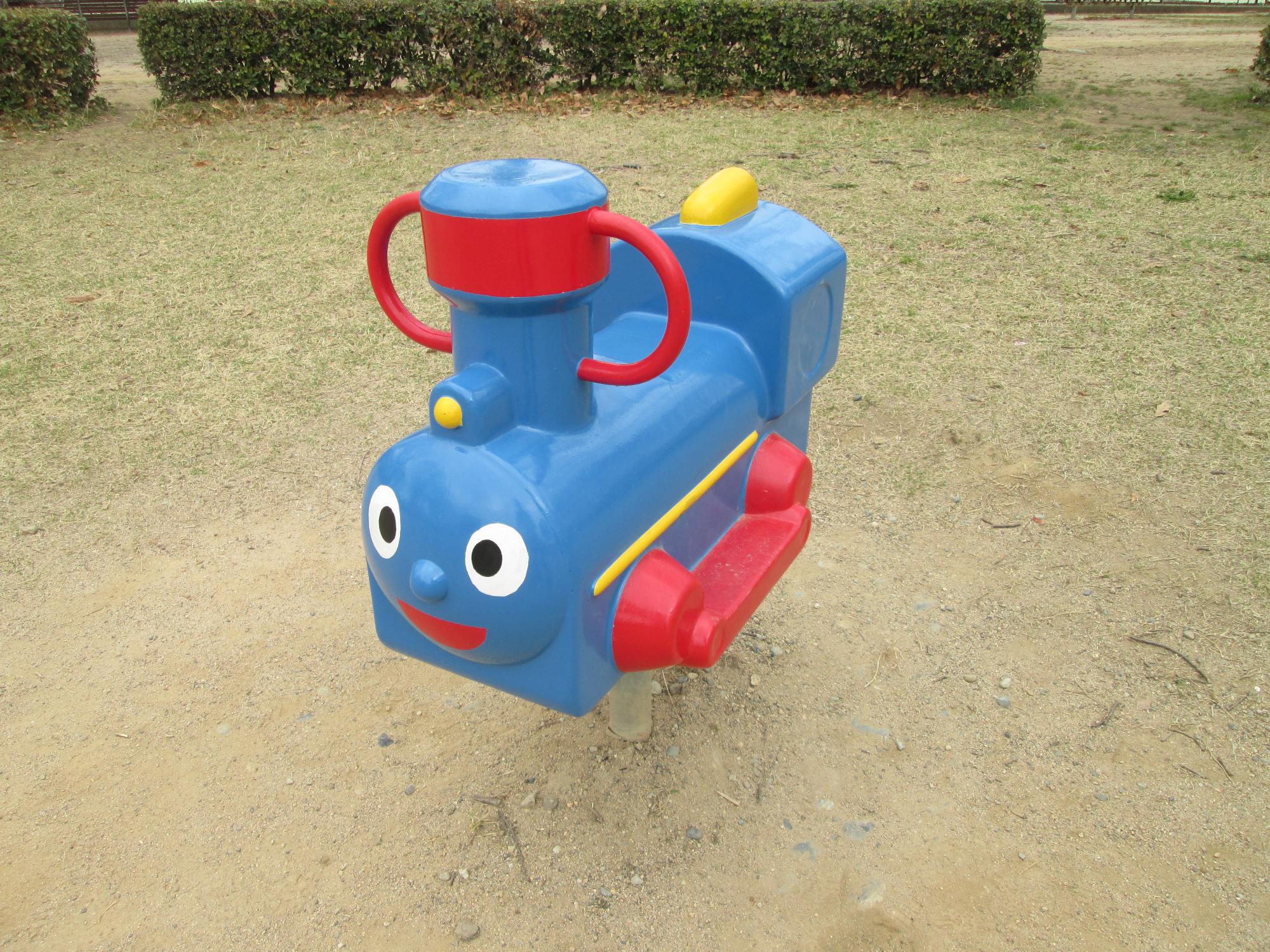 公園の中にある、紺色の機関車のスプリング遊具の写真