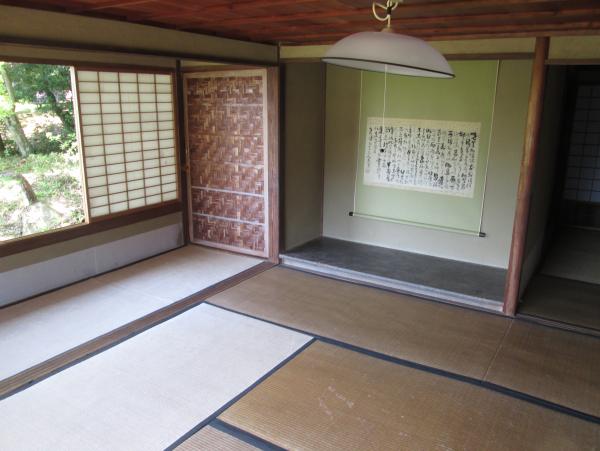 障子の窓から外の緑の景色が見える掛け軸の飾られた畳の聚遠亭の茶室の写真