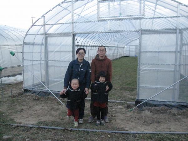 ビニールハウスの前で黒田さんご家族4名で並んでいる写真