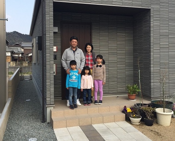 自宅の玄関前でFさんご家族5名が並んでいる写真