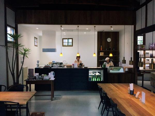 手前にテーブル、正面奥にレジがある店内の写真