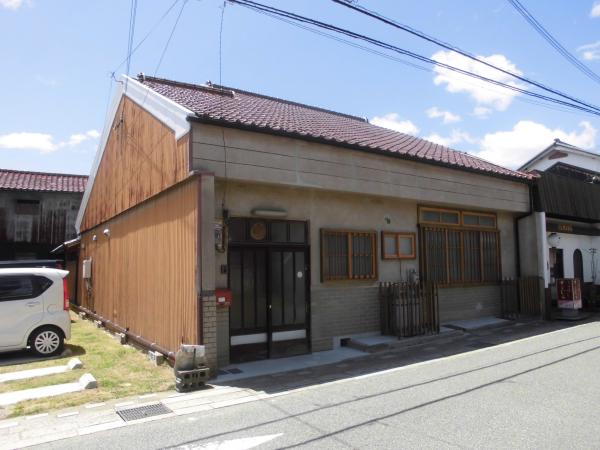 朱色の瓦になり庇がなくなった入り口の修理後の建物の写真