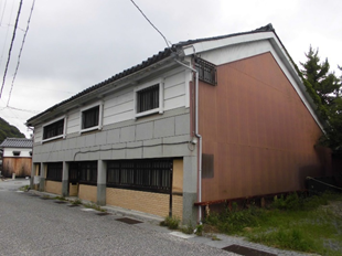 右側が薄い朱色の外壁の2階建ての建物の写真