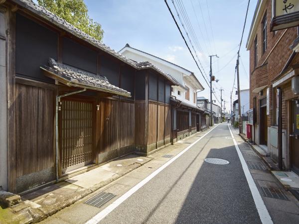道路の右側は2階建てのレンガ風の洋風の家、左側には瓦屋根が付いた塀があり引き戸の入口の上にも瓦屋根がある塀が立つ川原町の町並みの写真