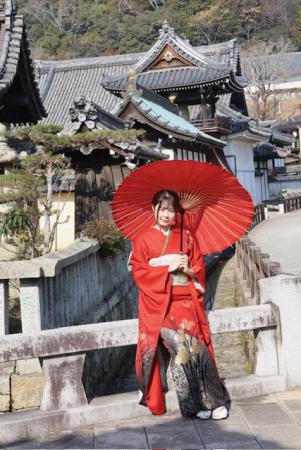 如来寺と橋の欄干に赤い着物を着た女性が腰かけている写真