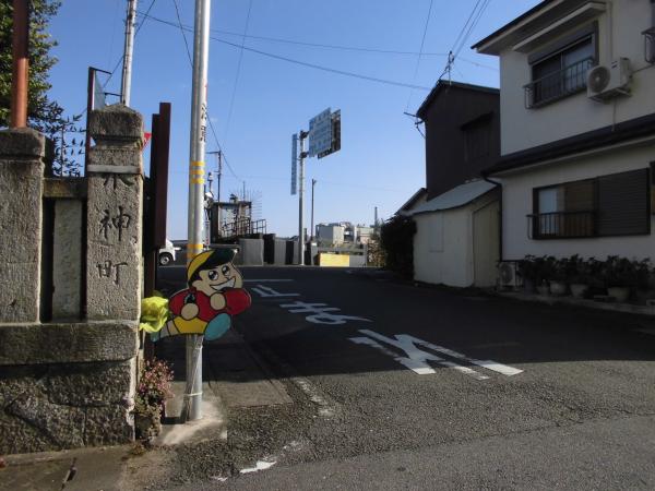 道路の左側には水神町と書かれた石碑があり、右側には白を基調とした2階建ての家が建つ九艘ノ町の写真