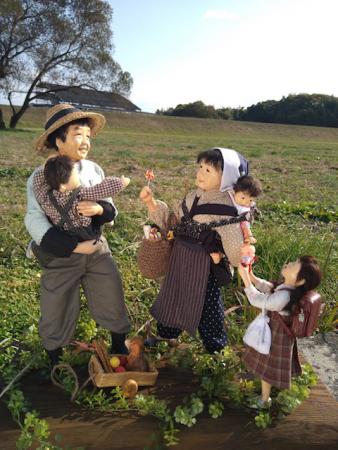 昭和時代のもんぺ姿の父母が小さな子供を負ぶったり抱っこしてあやしている人形の写真