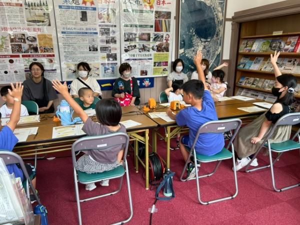 椅子に座った子供達がまっすぐに手を上げ挙手をしている様子を写した写真