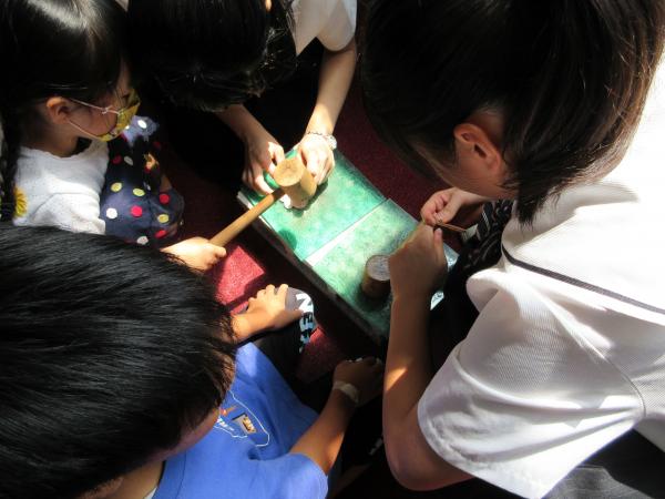 子供達の革に穴をあけている講師の女子学生2名の写真