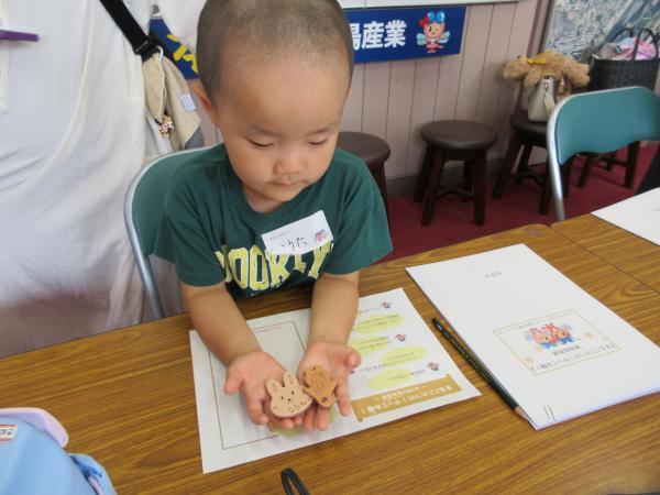 坊主頭の男の子が両手の手の平に出来上がったキーホルダーを2個のせている写真