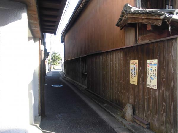 狭い路地に右側は木造の外壁の古民家、左側は白を基調とした家が建つ湯屋ノ小路の写真
