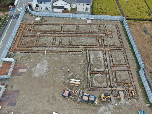 フェンスで囲まれた敷地内にL字型の枠でかたどられた仮設校舎の基礎工事を重機を使って開始された様子を上空から撮影した写真