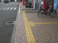 歩道面に視覚障害者誘導用ブロックが店内の入口に向かって敷設されている写真