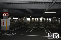 コンクリートの地面に白色の線が描かれた薄暗いイオンの屋内駐車場の写真