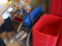 赤い買い物かごが重ねられた横に、折りたたまれた車いすが置かれている写真
