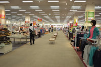 衣類が並んでいるお店の間の通路が広く設けられているショッピングモール内の写真
