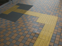 タイルの歩道面に視覚障害者誘導用ブロックが敷設されている写真