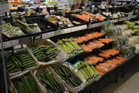 エンド売り場に陳列されたきゅうりやアスパラや人参などの野菜の写真