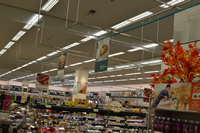 商品棚と天井の間に吊り下げられた商品名と商品の写真がのった看板の写真