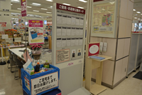 エスカレーターから降りた傍にイオンの即日便のポップと側面に「ご自宅まで即日お届けします。」と書かれたポップが貼られた青色の箱の中に見本商品が入れられ、右側にお客様の声が書かれた「ご意見・お返事公開ボード」が設置された写真