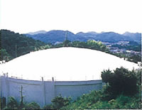 山に囲まれた敷地内に、ドーム型の屋根で白壁の円柱型の建物が設置された旭配水池の写真