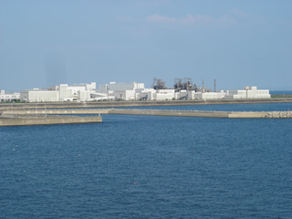 広大な敷地内に大きな煙突や幾つもの白壁の建物が建ち並んでいる兵庫県揖保川浄化センターを、センターの全体が写るように海を挟んだ場所から撮影した写真
