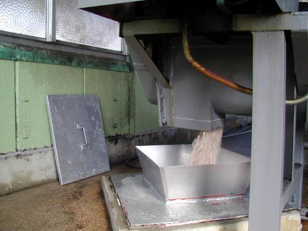 機械の下から大豆と小麦を混ぜたものが出てきている写真