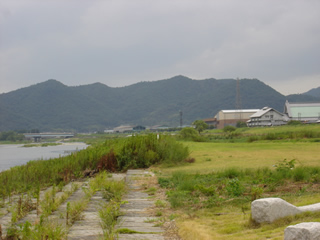 山並みの手前の揖保川に橋が架かり、周囲に建物や芝生広場の公園が設置されている写真