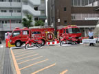 駐車場に2台の消防活動二輪車と3台の消防車が停車している写真