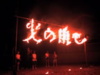 太陽が沈んで真っ暗闇のなか、火の用心の文字が燃えて浮かび上がっている写真