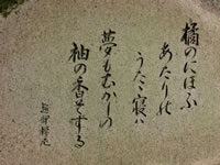 石碑のようなものに右から縦書きで短歌のように「橘のにほふあたりのうたた寝は夢もむかしの柚の香そする」と書かれている写真
