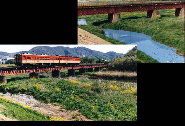 鉄道の高架橋の下をなだらかに流れる川の水の色が水色に濁っていたのが、埋め立てられ高架橋の上を電車が走っている写真