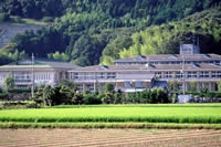 山の麓にある校舎や体育館を、近隣の田畑の傍から撮影した揖西西小学校の写真