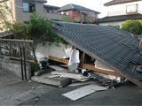地震で屋根のみ残して潰れてしまった家の写真