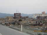 道路脇に骨組みだけが残った建物や津波で流されてきたものが散乱している写真