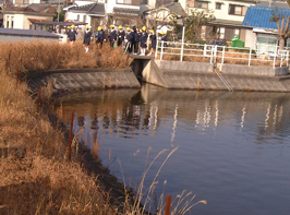 住宅街にある池の側を児童が歩いている写真
