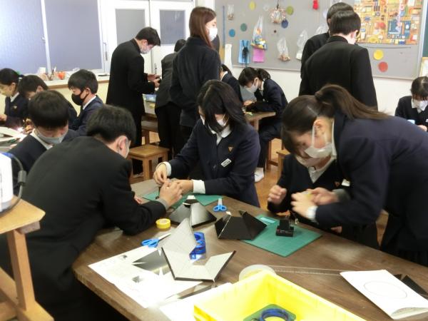 教室で生徒が2人から3人で1組になり、机の上で工作をしている写真