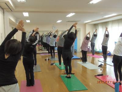 両手を上に上げた状態で、右手で左を右側に引っ張り体を伸ばしているストレッチヨガの写真