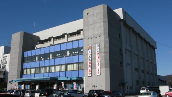薄い灰色の外壁で大きな建物の龍野体育館を、斜め前から写した写真