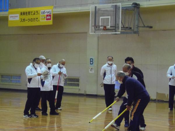 運動着姿の男性たちが、体育館の中で障害者スポーツの指導者向け講習を受けている写真