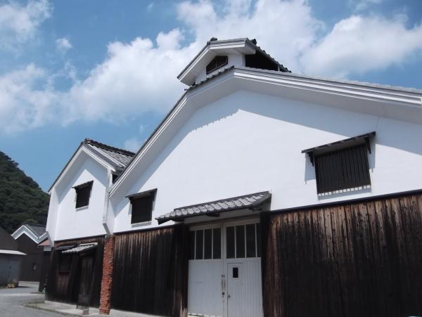 建物の外壁の上半分が白く目の細かい格子がついた窓があり、下半分は木の板壁になっているヒガシマル醤油元本社工場の写真