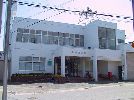 入り口にポストがあり白い外壁で大きな窓がたくさんある2階建ての黒崎公民館の建物全体を斜め前から写した写真