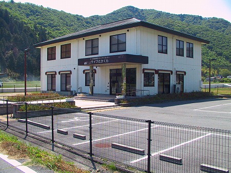 フェンスで囲われたたつの市東栗栖コミュニティセンターの白い外壁の二階建ての建物全体を写した写真