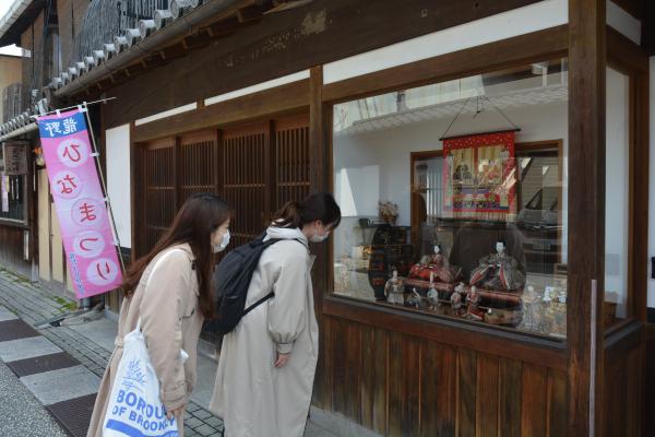 龍野ひなまつりで店舗のガラスケースに展示された雛人形を見ている2人の女性を撮影した写真