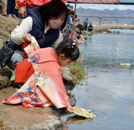 龍野ひな流しで流しびなを揖保川へ流す女の子と落ちないように支える母親を撮影した写真